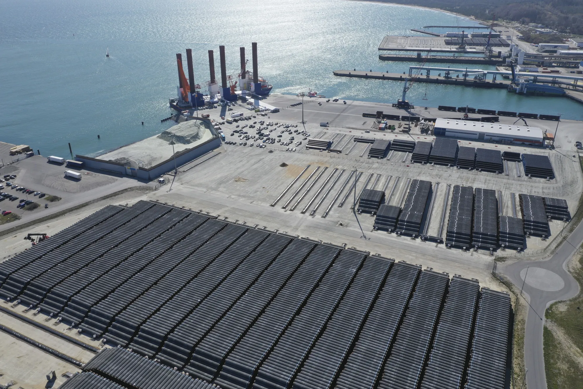 Sections of pipe for the Nord Stream 2 gas pipeline sit in storage as the MPI Resolution turbine installation vessel sits moored at Mukran Port in Sassnitz.