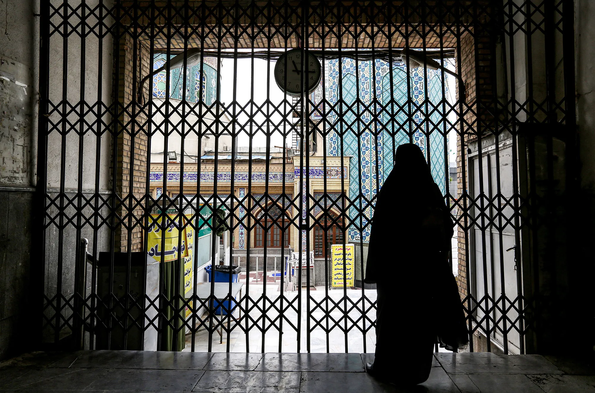 A woman stands by the closed gate outside the Imamzadeh Saleh in the Iranian capital Tehran's Shemiran district on April 25.