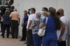 Voters wearing protective masks stand in line to cast ballots at an early voting polling location for the 2020 Presidential election in Miami, Florida, U.S., on Monday, Oct. 19, 2020.