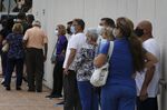 Voters wearing protective masks stand in line to cast ballots at an early voting polling location for the 2020 Presidential election in Miami, Florida, U.S., on Monday, Oct. 19, 2020. 