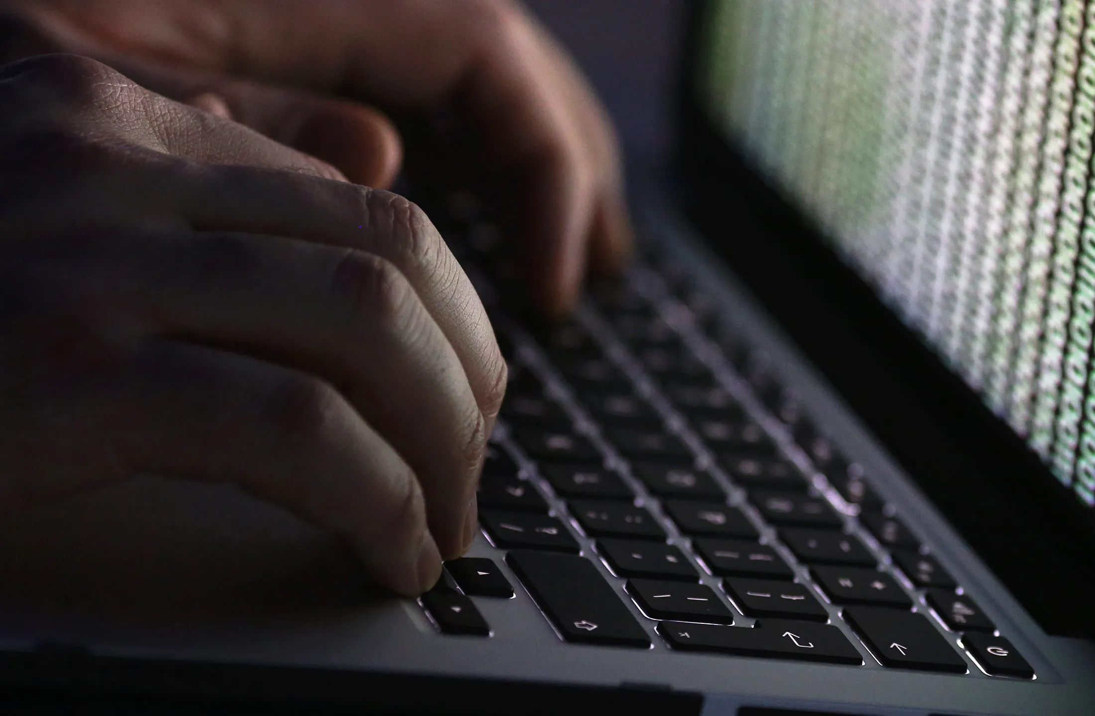 A stream of binary coding, text or computer processor instructions, is seen displayed on a laptop computer screen as a man works to enter data on the computer keyboard in this arranged photograph in London, U.K., on Wednesday, Dec. 23, 2015. The U.K.s biggest banks fear cyber attacks more than regulation, faltering economic growth and other potential risks, and are concerned that a hack could be so catastrophic that it could lead to a state rescue, according to a survey.
