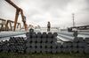 A worker stands on bundles of steel pipe stacked at a stockyard on the outskirts of Shanghai, China.