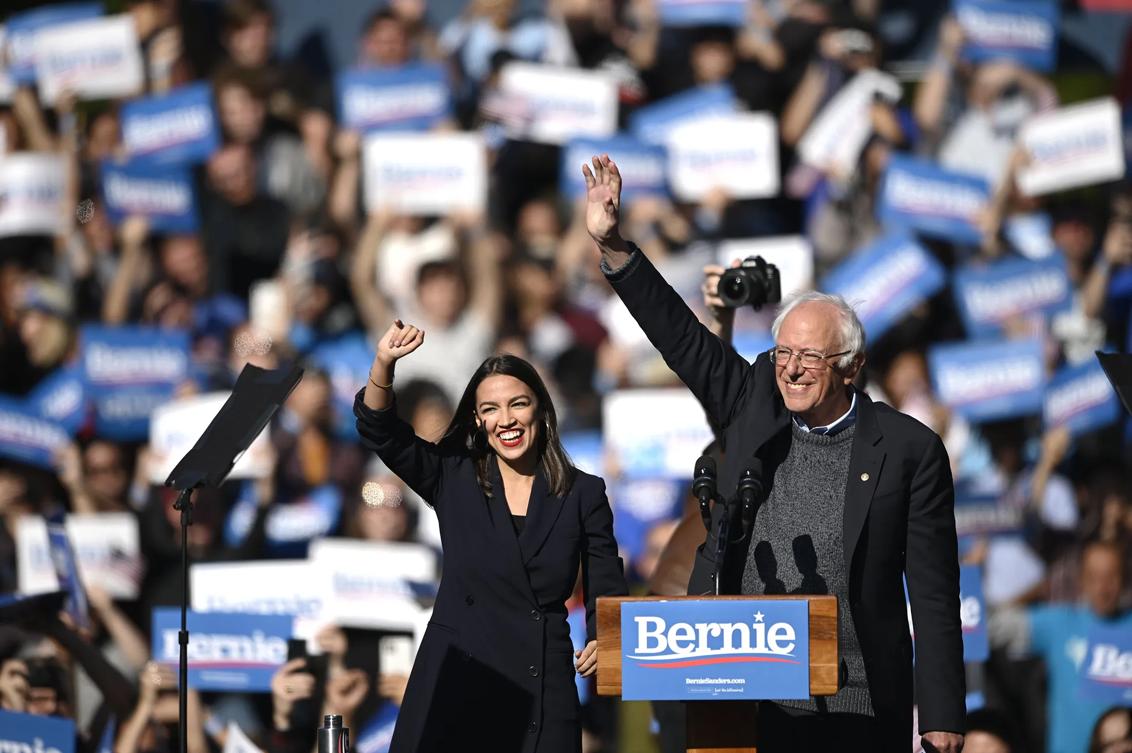Bernie Sanders and Alexandria Ocasio-Cortez wave during a campaign rally on Oct. 19