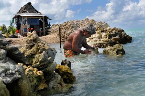 A man rebuilds his sea wall to protect his home in the village of Abarao on the island of Tarawa.