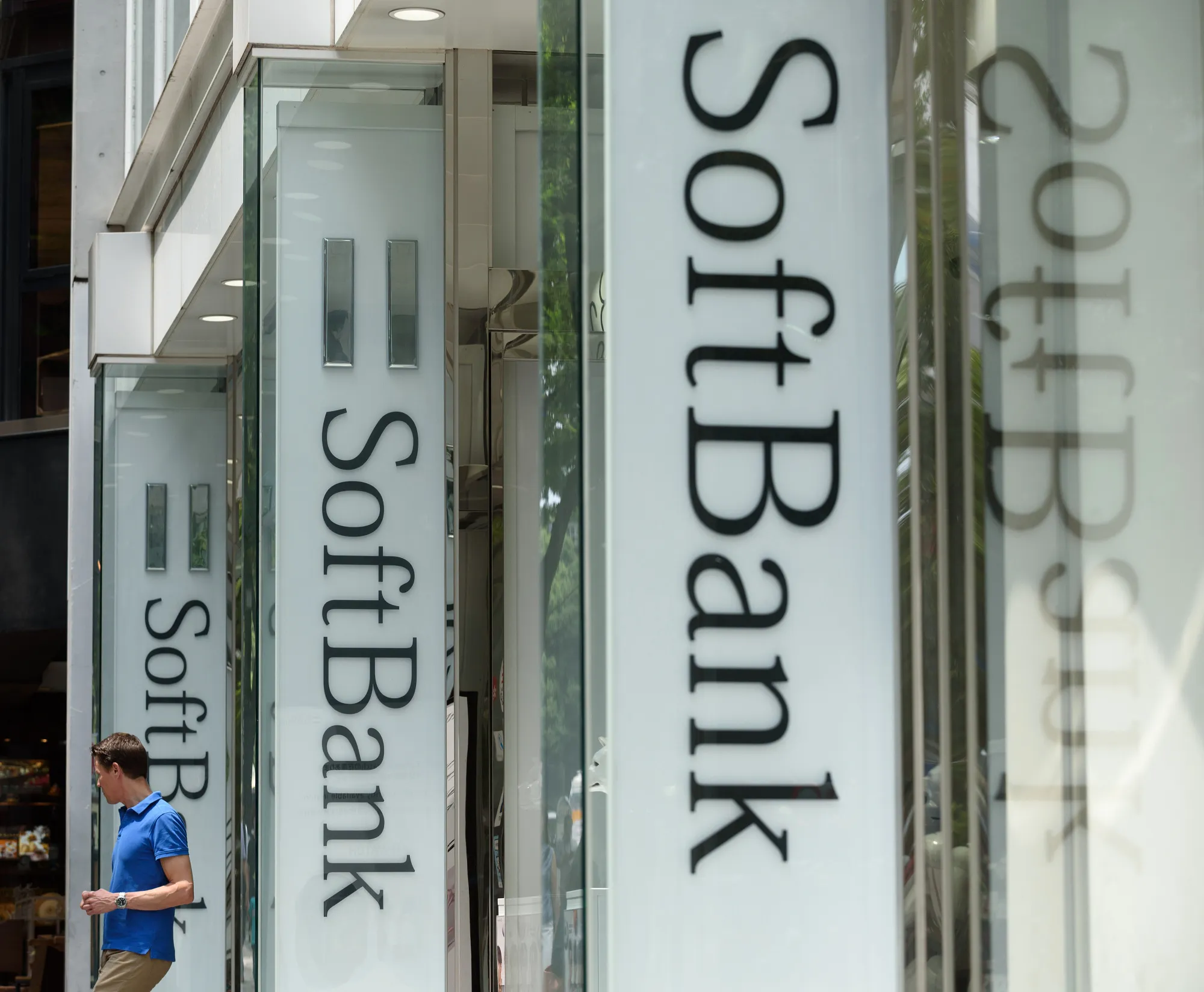 A man exits a SoftBank Group Corp. store in Tokyo, Japan, on Tuesday, July 19, 2016. SoftBank plunged in Tokyo after unveiling its $32 billion takeover of chip designer ARM Holdings Plc, a deal that marks founder Masayoshi Son's biggest gamble so far on the future of technology.