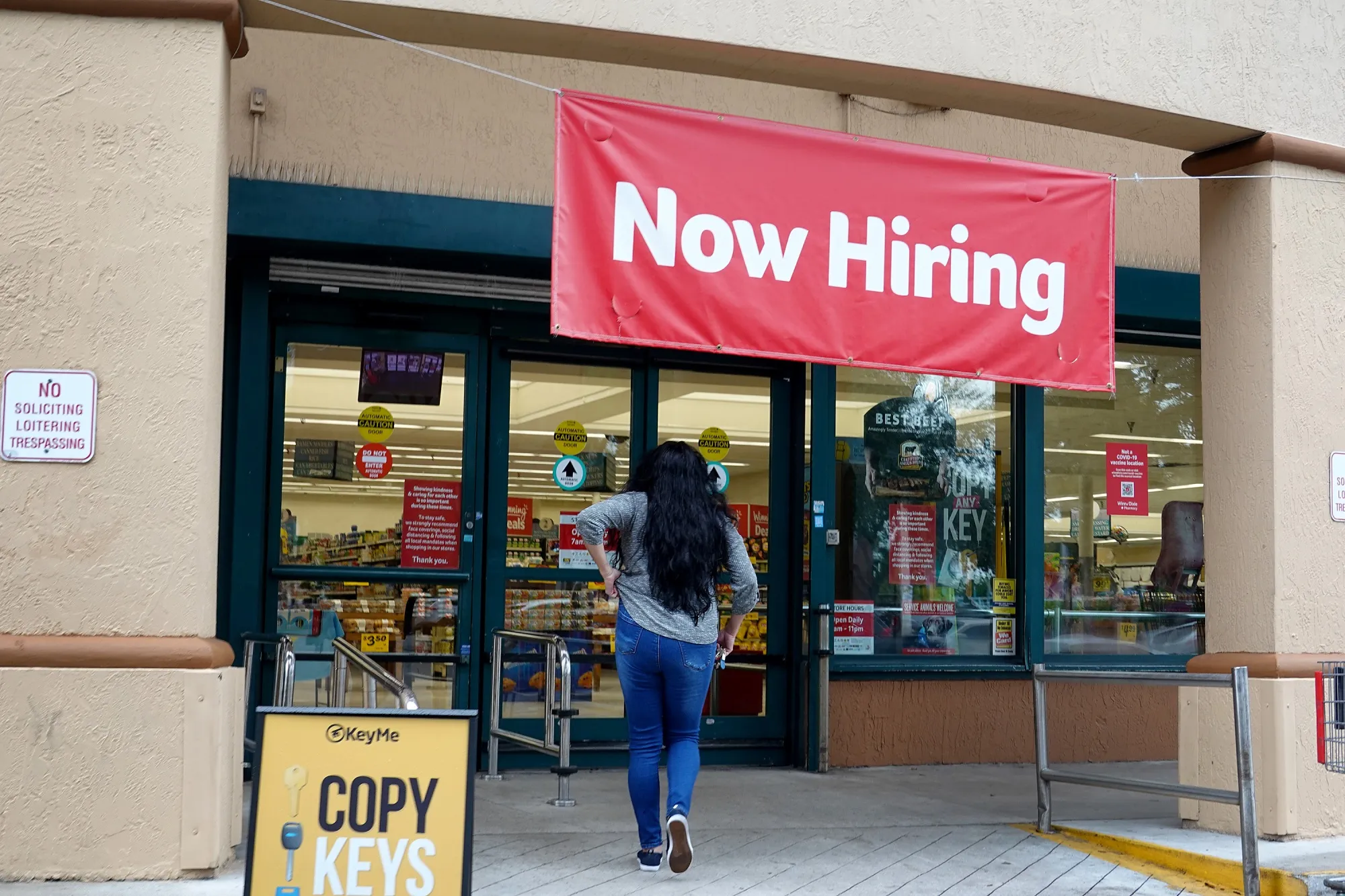 A Now Hiring sign hangs near the entrance to a supermarket in Hallandale, Florida.