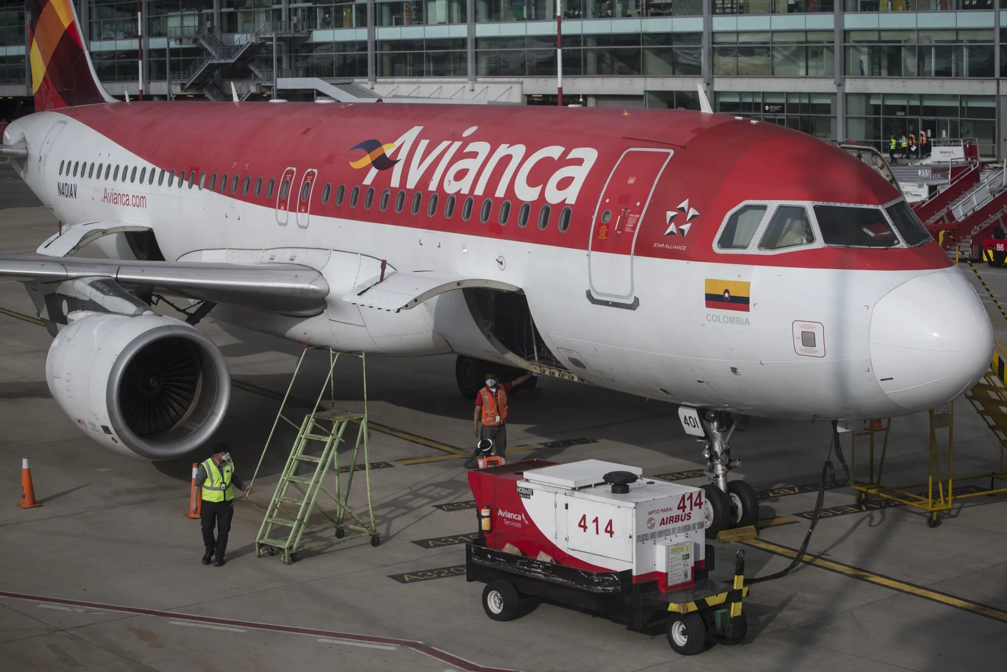 Workers stand beside an Avianca aircraft at El Dorado International Airport in Bogota, Colombia.