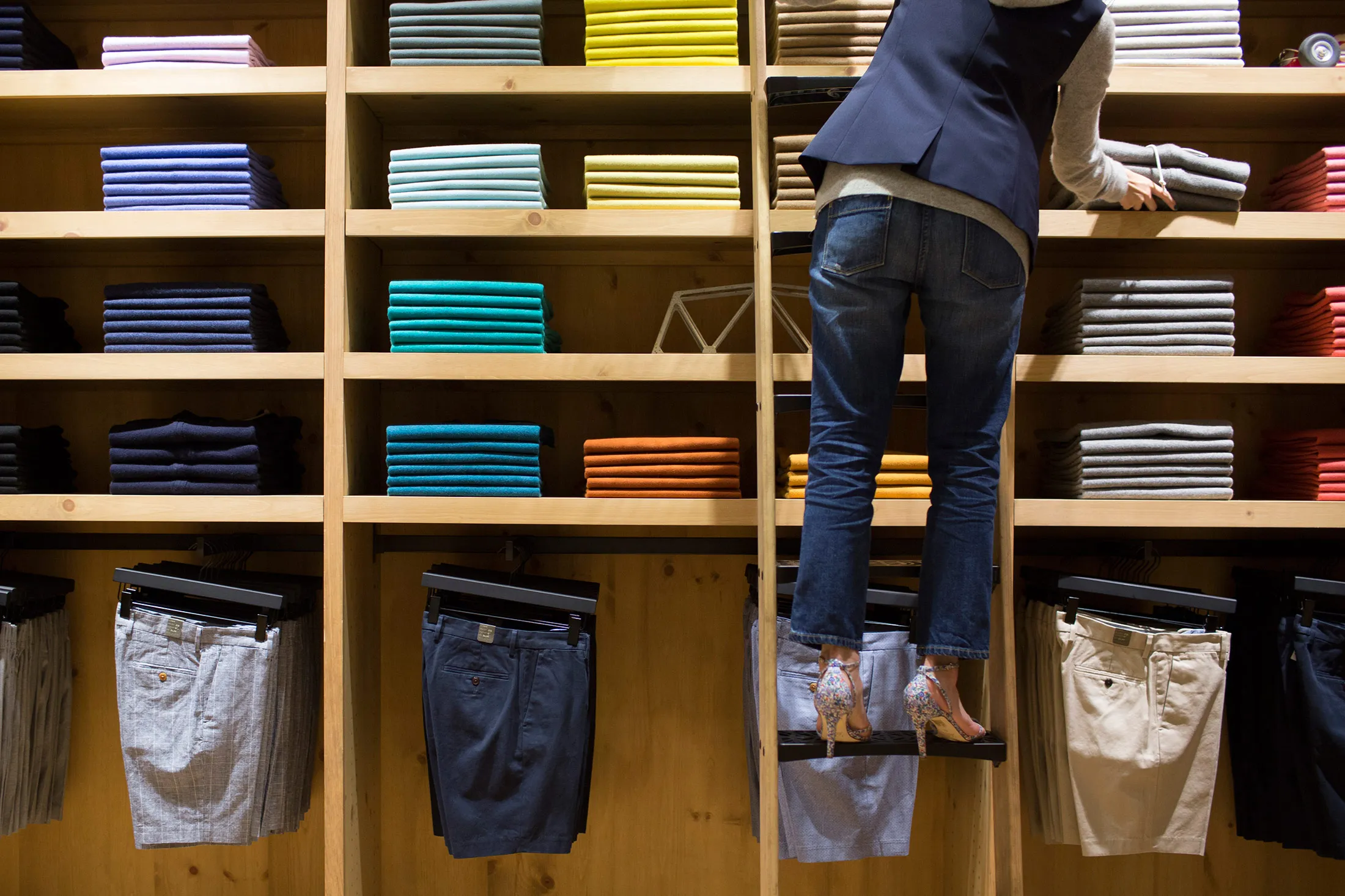 An employee on a ladder arranges shirts at J. Crew's men's store in the Central district of Hong Kong.
