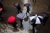 Pedestrians with umbrellas walk along Wall Street near the New York Stock Exchange (NYSE) in New York.