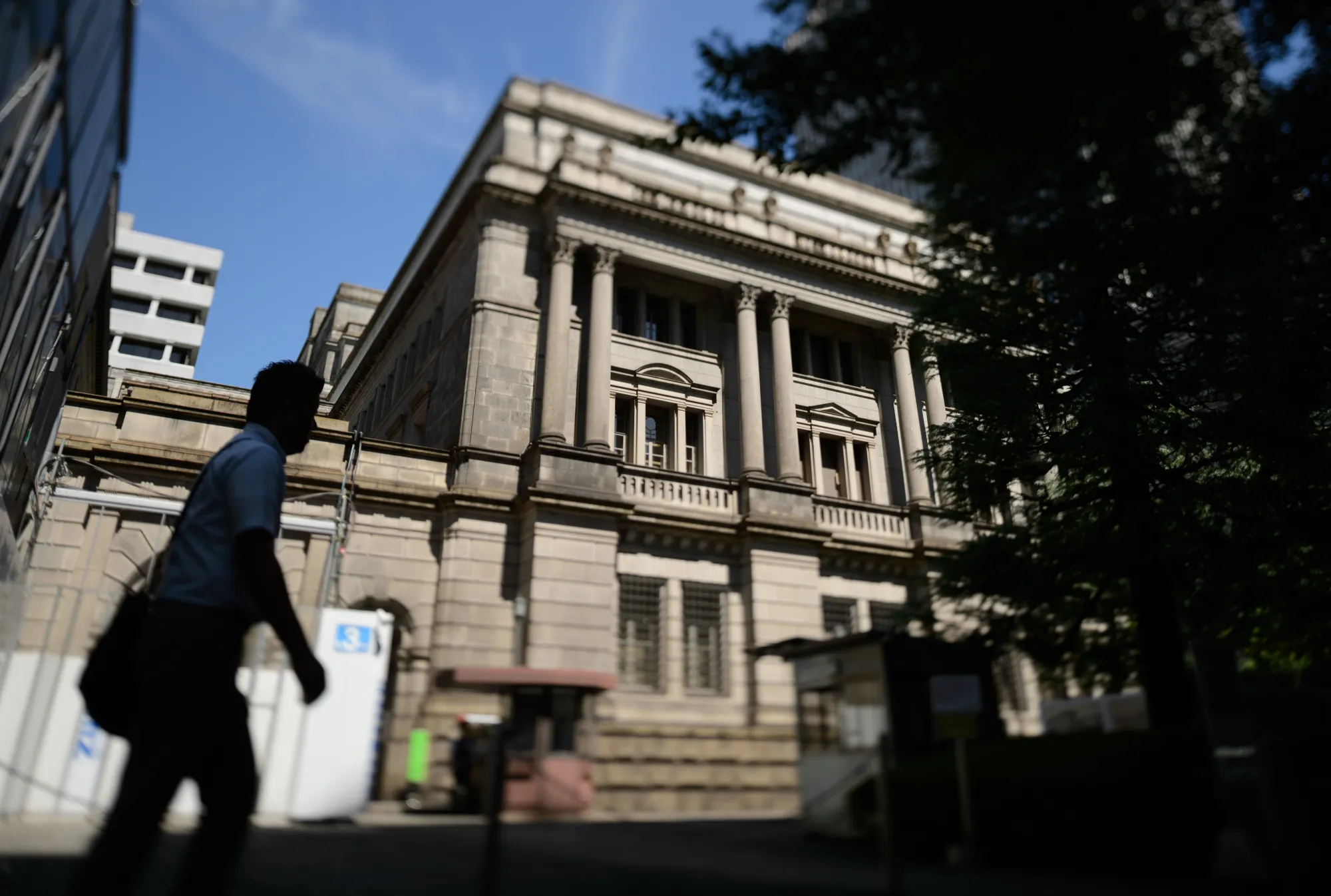 (EDITORS NOTE: Image was created using a variable planed lens.) A pedestrian walks past the The Bank of Japan (BOJ) headquarters in Tokyo, Japan, on Wednesday, Sept. 13, 2017. The BOJ's next monetary policy meeting is scheduled for Sept. 21. The central bank pushed back in July the projected timing for reaching its 2 percent inflation target for the sixth time as economic growth failed to drive price gains.