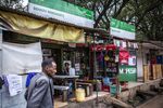 A pedestrian passes retail kiosks offering Safaricom mobile money services in Nairobi, Kenya.