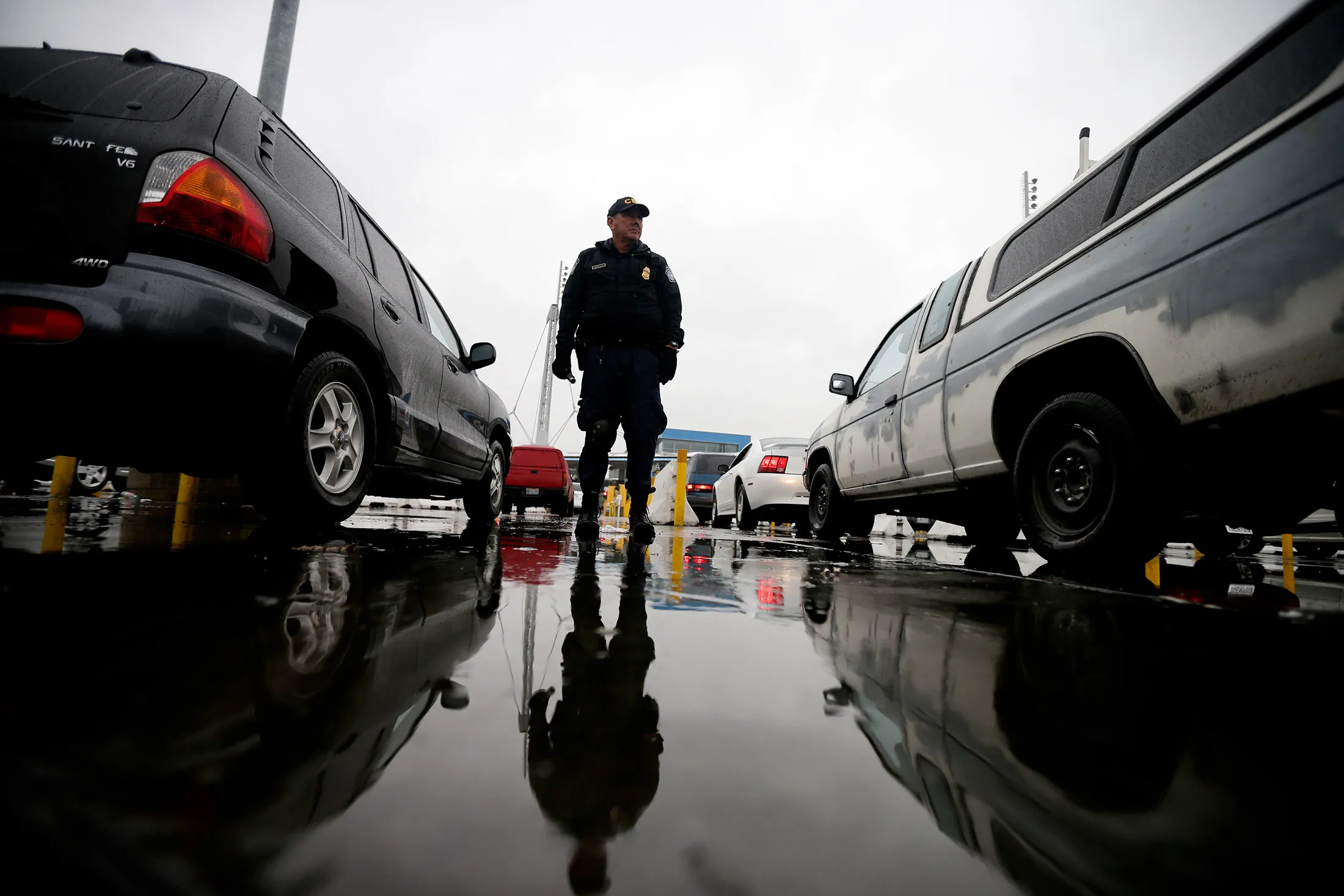 An Immigration and Customs Enforcement (ICE) agent watches cars as they waits to enter the United States from Tijuana, Mexico through the San Ysidro port of entry in San Diego, on Dec. 3, 2014.
