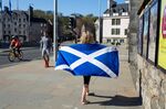 A girl walks with her towel featuring the national flag of Scotland near the Scottish Parliament in&nbsp;Edinburgh on&nbsp;April 25.
