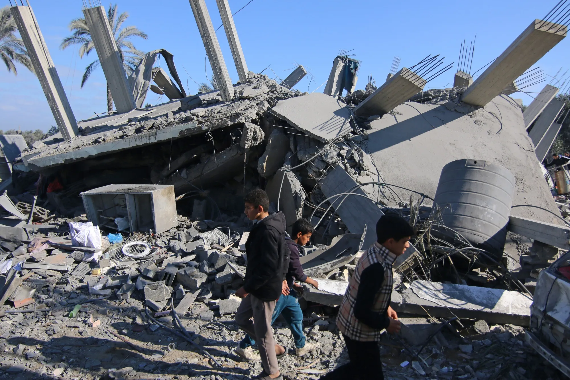 Palestinians walk across the rubble of a collapsed building following an Israeli airstrike in the Zuwayida district of central Gaza on Feb. 22.