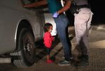 A two-year-old Honduran child cries as her mother is searched and detained near the U.S.-Mexico border on June 12.