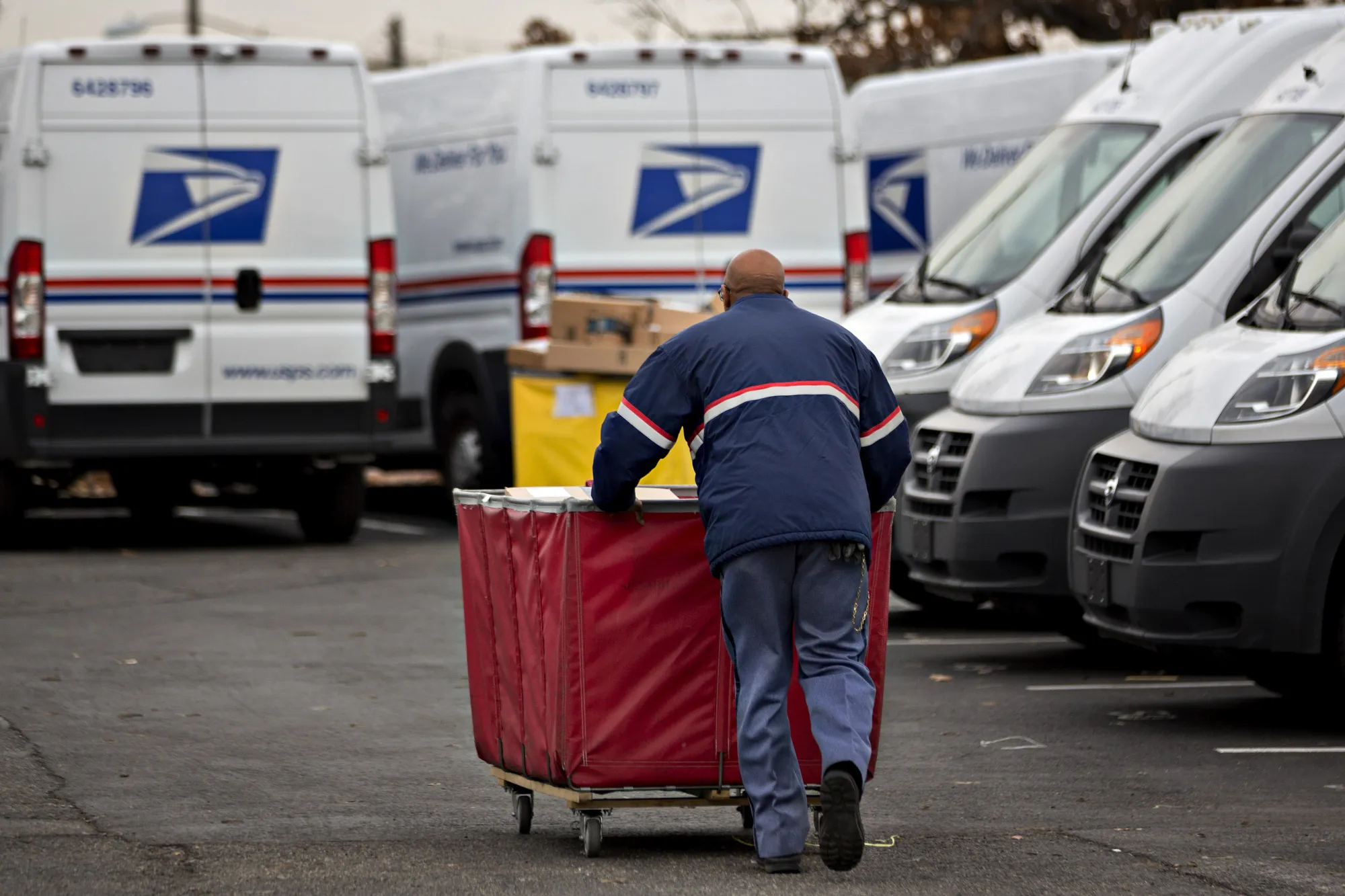 A letter carrier pushes a package bin towards a delivery vehicle at the United States Postal Service (USPS) Joseph Curseen Jr. and Thomas Morris Jr. processing and distribution center in Washington, D.C.