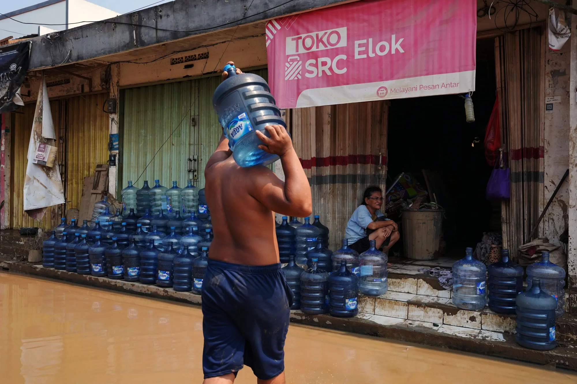 A worker carries a jug&nbsp;of water through floodwaters in Bekasi, Indonesia, on March 6, 2025.&nbsp;