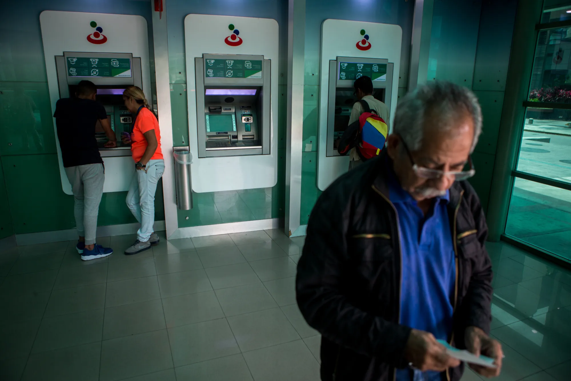 Customers use&nbsp;ATMs&nbsp;at a Banesco Banco Universal CA bank branch in Caracas.