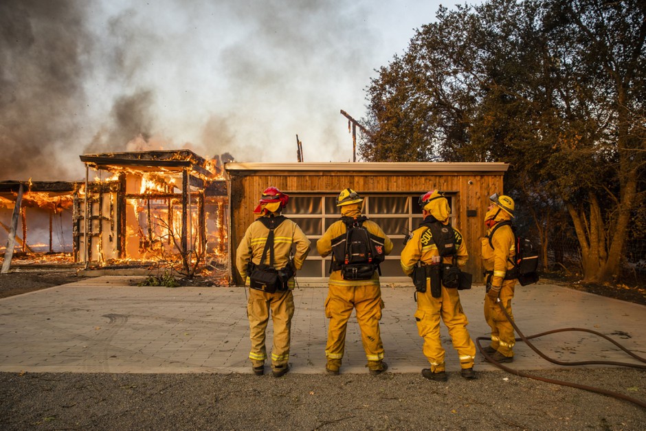 Firefighters survey a home burning along Highway 128 during the Kincade fire in Healdsburg, California, in October 2019.