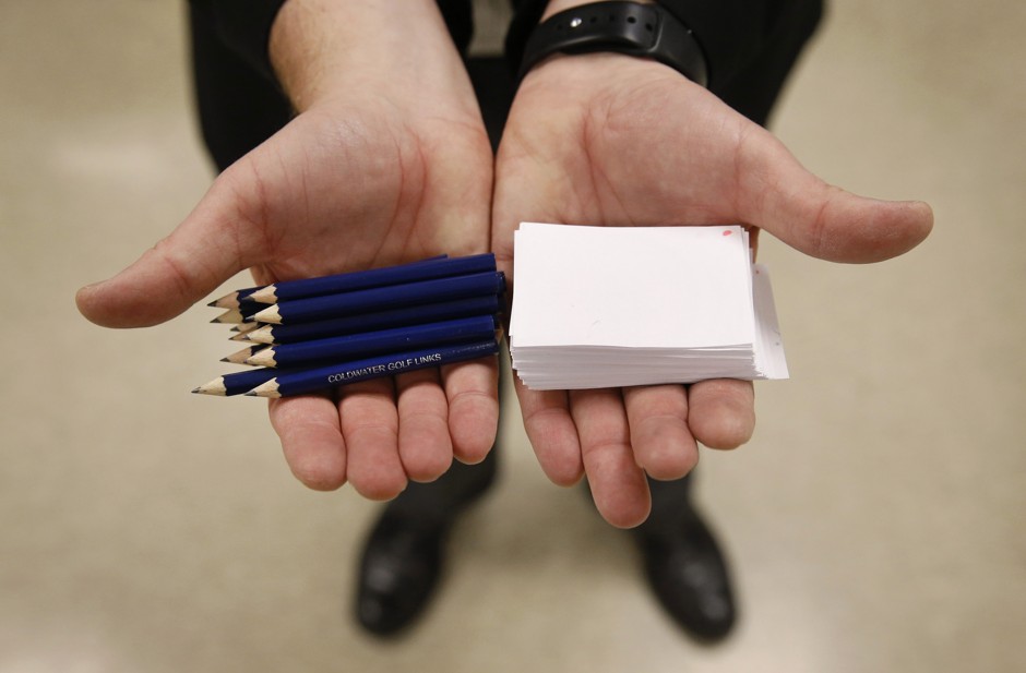 Precinct chair John Anderson holds pencils and slips of paper to be used by voters to select their candidates at a Republican party caucus in Nevada, Iowa.