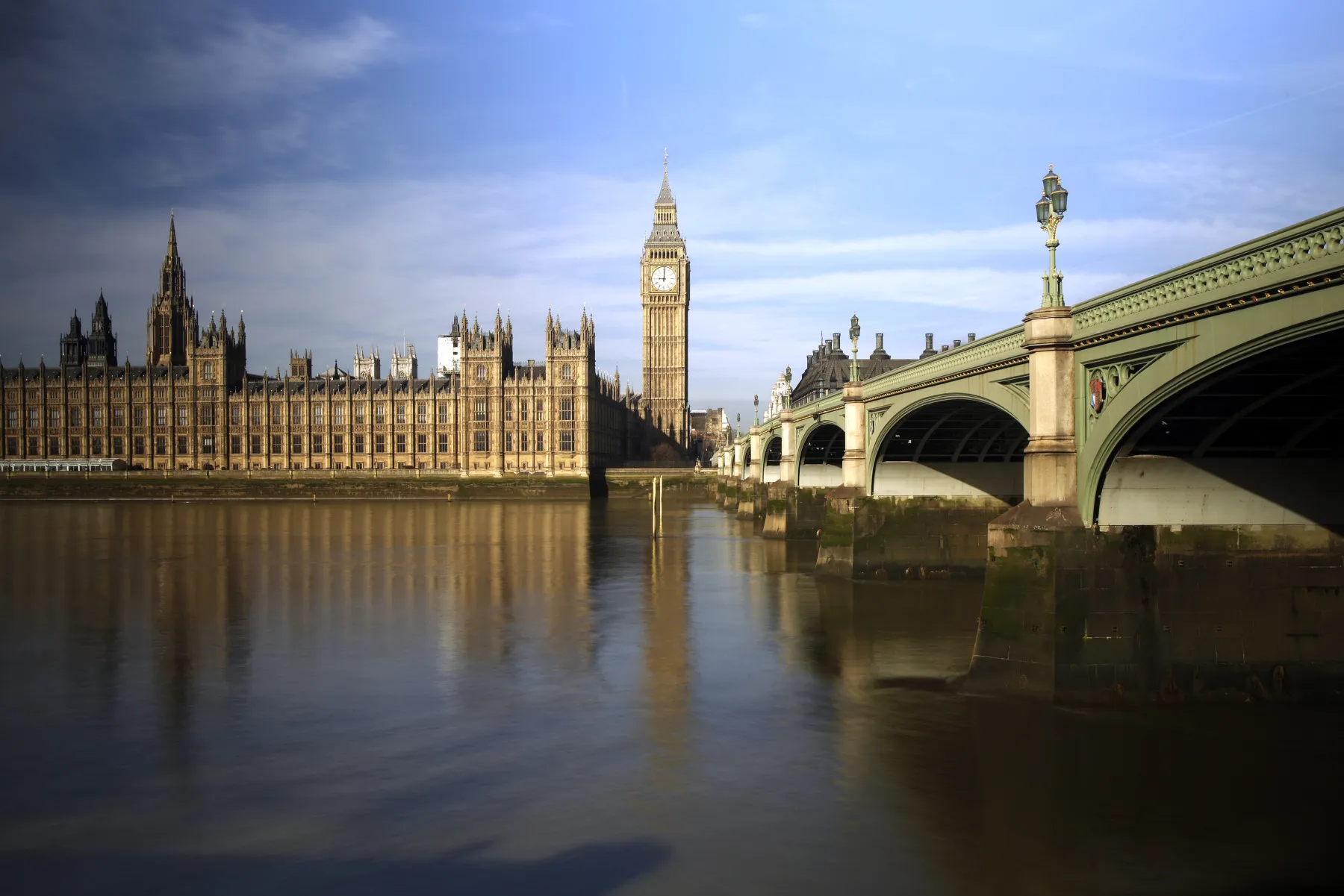 The Big Ben clock tower and the Houses of Parliament, left, are seen standing alongside the River Thames and Westminster Bridge in London, U.K.