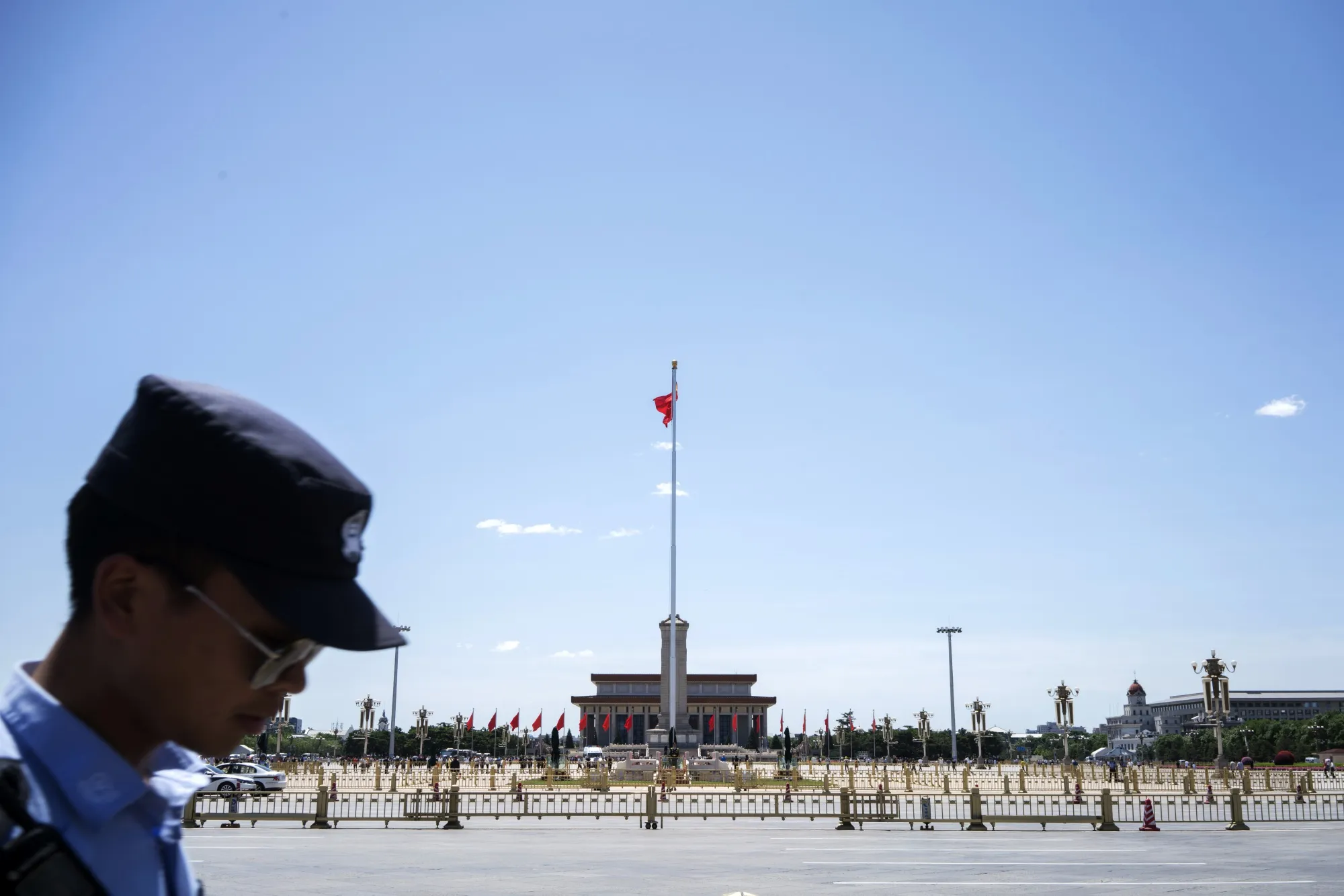A police officer walks past the Monument to the People's Heroes and the Mausoleum of Mao Zedong at Tiananmen Square in Beijing.