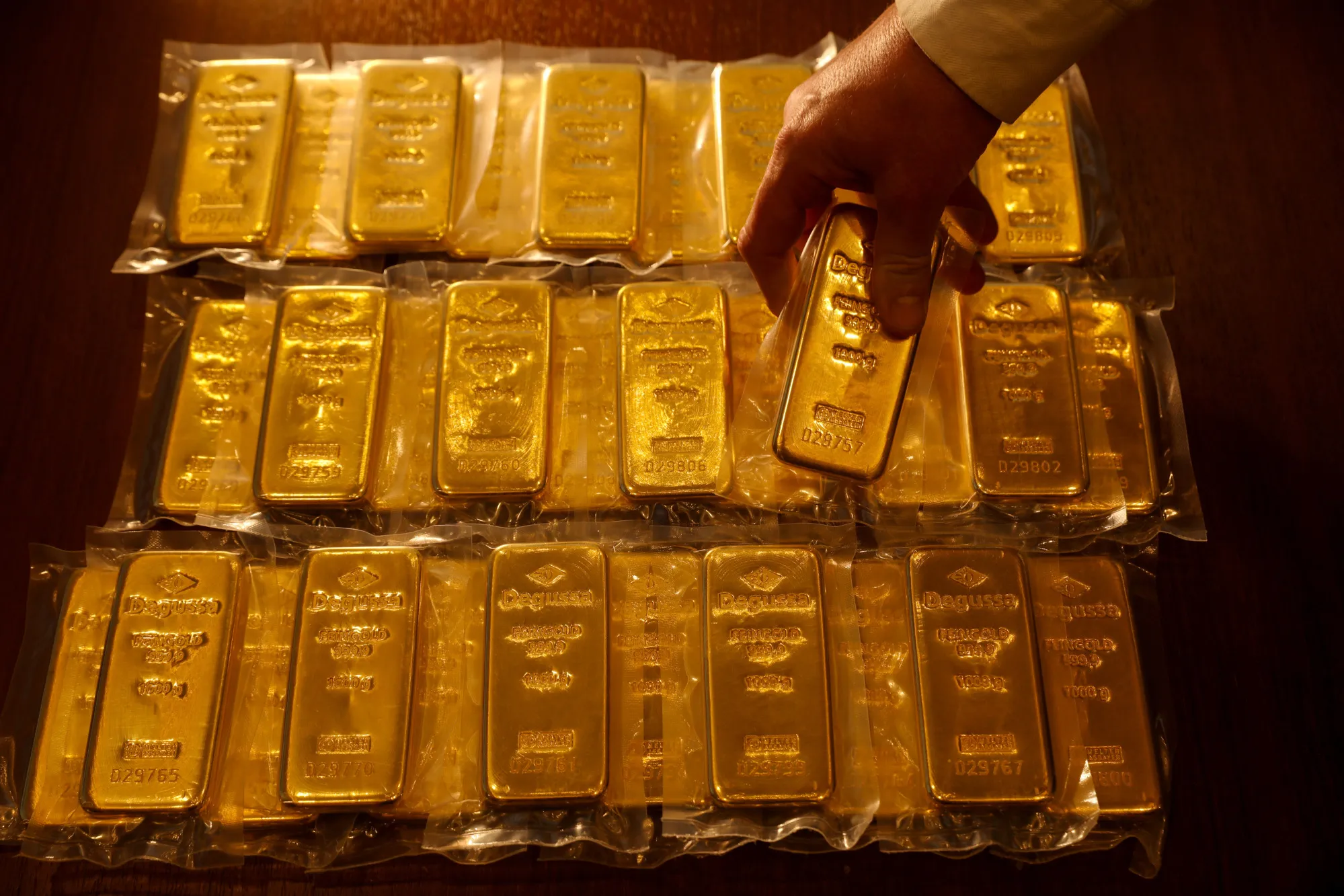 An employee holds one of thirty two, one kilogram bars of gold, worth a total of approximately one million British pounds sit on a table at the Sharps Pixley Ltd. showroom in this arranged photograph in London, U.K., on Thursday, Jan. 18, 2018. Amid the wild Bitcoin ride that’s wiped more than 40 percent off the cryptocurrency's price in a month, a pattern may be emerging: sellers are switching out of digital gold and into the real thing.
