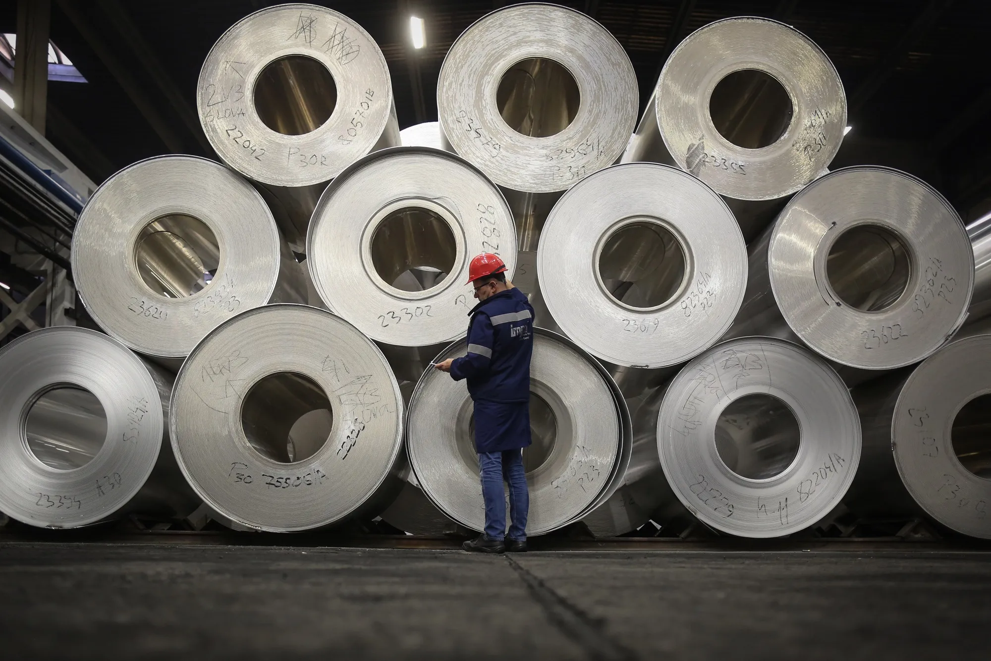 A worker checks inventory of sheet aluminum rolls in a storage area in Sevojno, Serbia.