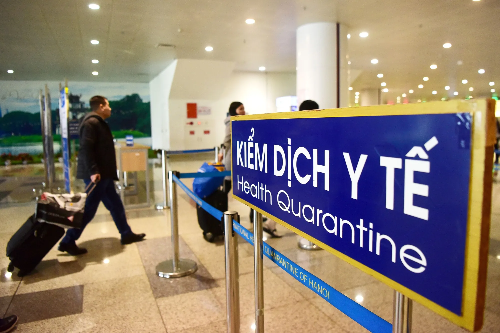 Arriving passengers walk past a health quarantine sign at Noi Bai International Airport in Hanoi.