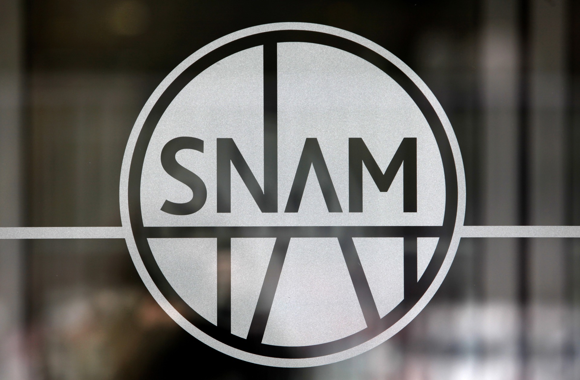 The logo of Snam SpA, sits on a door at the company's headquarters in Milan.