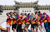 Women and men in bright rainbow shirts hug each other in a line