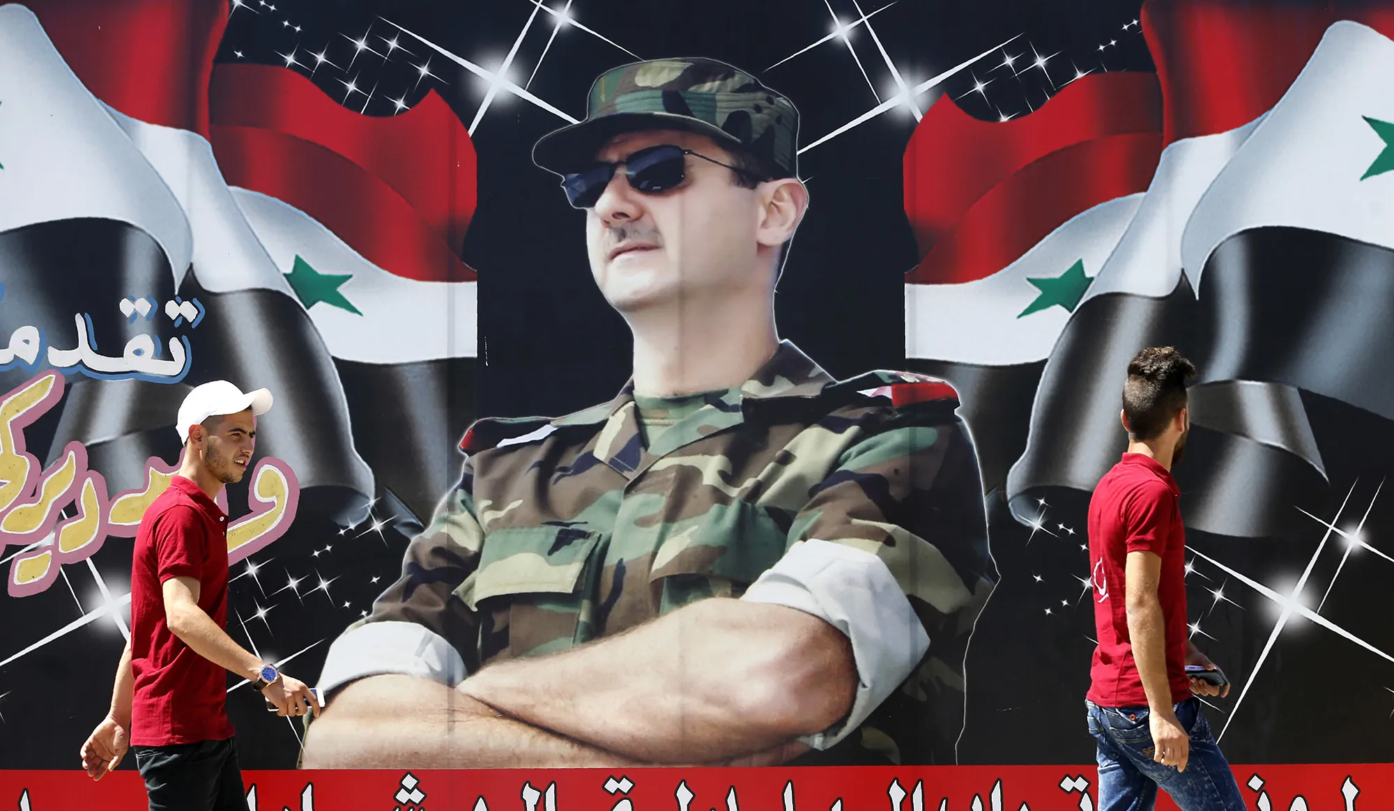 Pedestrians walk past a billboard of Bashar al-Assad in Damascus.