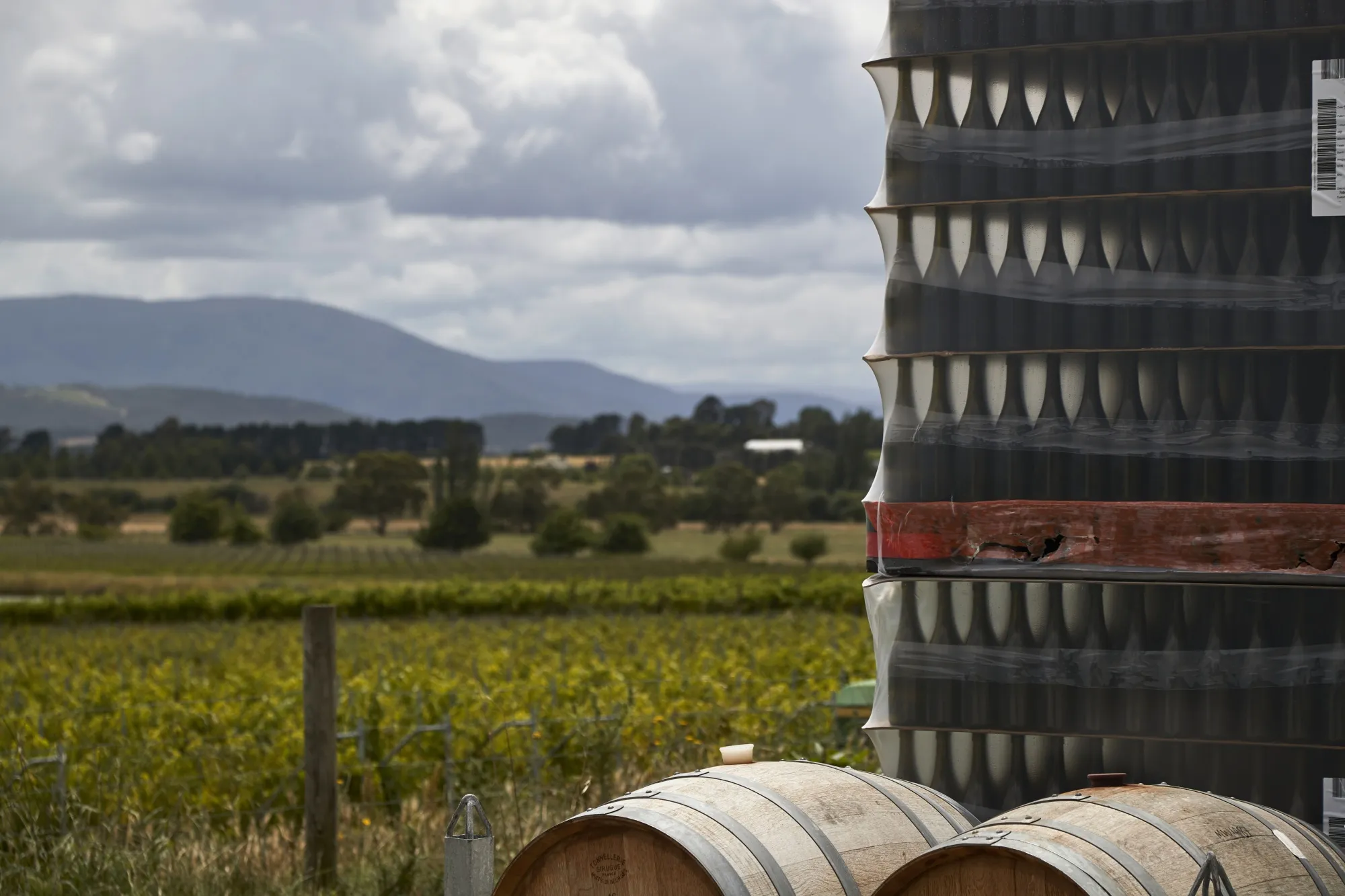 Wine barrels and pallets of bottles stacked at a winery in the Yarra Valley, Victoria, Australia.