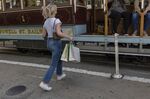 A commuter carrying shopping bags boards a trolley on Powell Street in San Francisco.