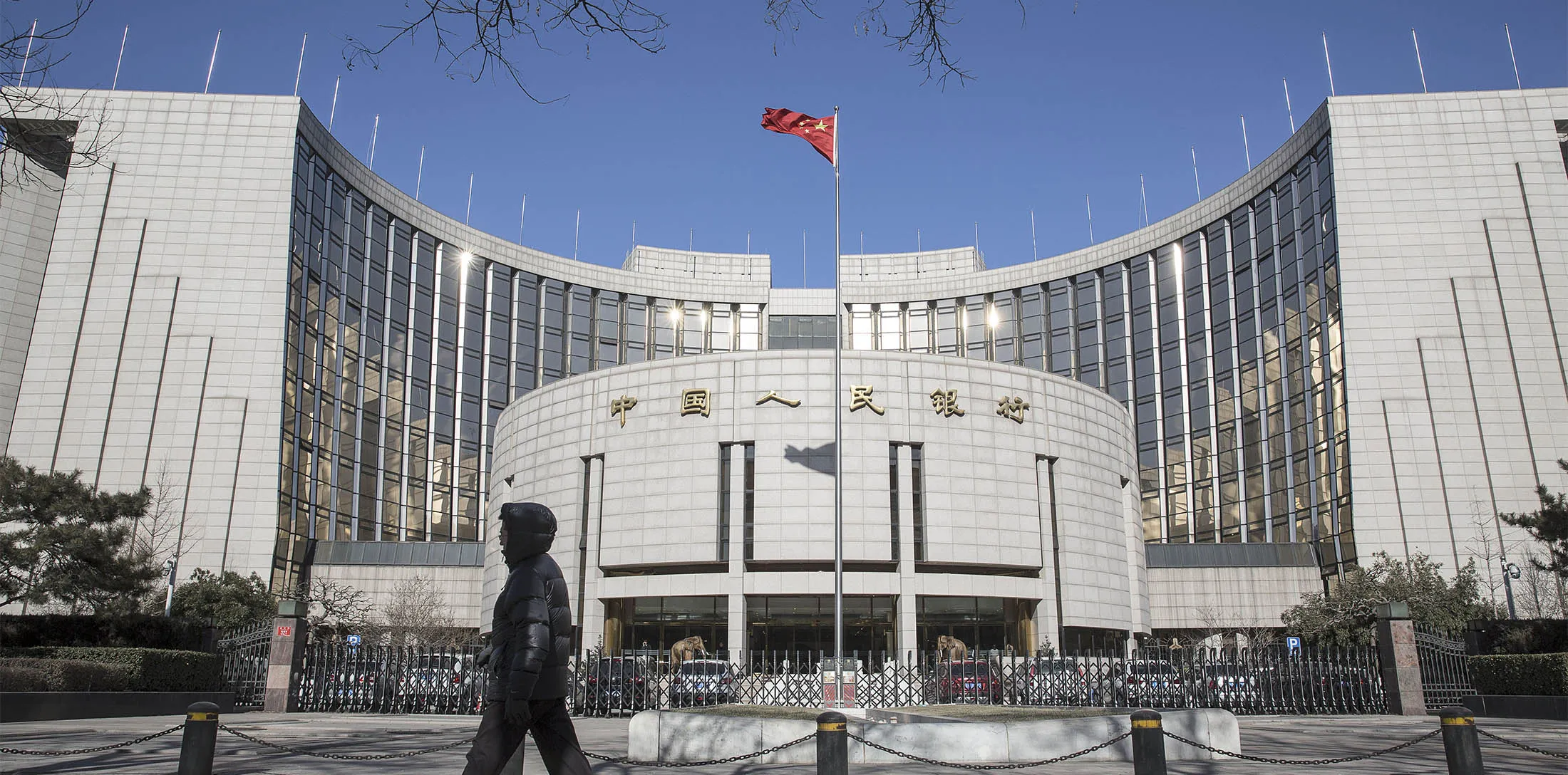 A pedestrian walks past the People's Bank of China (PBOC) headquarters in Beijing, China, on Monday, Jan. 18, 2016. China's economy slowed in December, capping the weakest quarter of growth since the 2009 global recession, as the Communist leadership struggles to manage a transition to consumer-led expansion.
