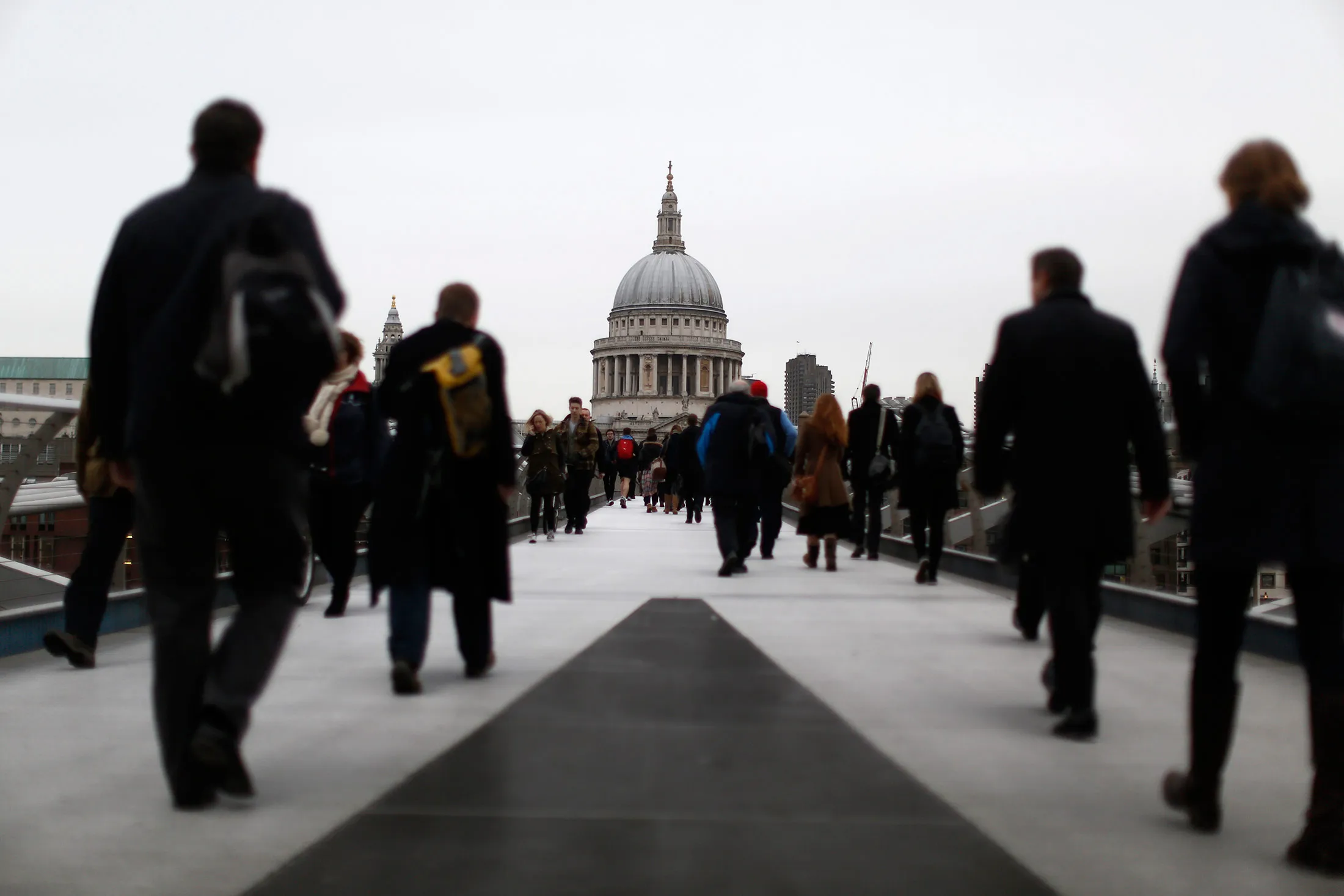 Commuters walk across the Millennium Bridge towards St. Paul's Cathedral.
