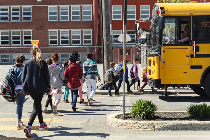 Kids in line crossing street to get on school bus.