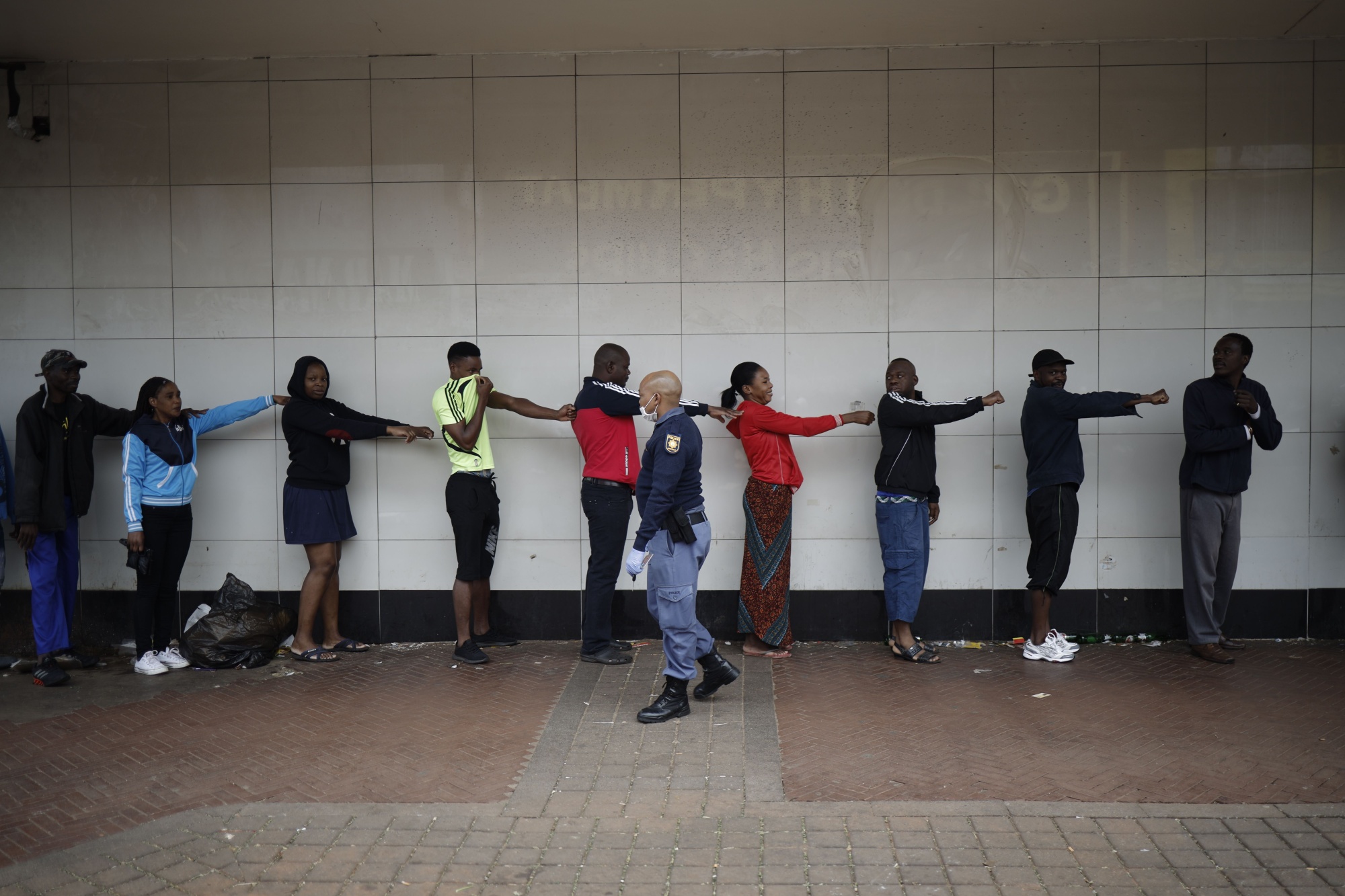 A member of the South African Police Service (SAPS) enforces social distancing of shoppers outside a supermarket in Yeoville, Johannesburg, on March 28.