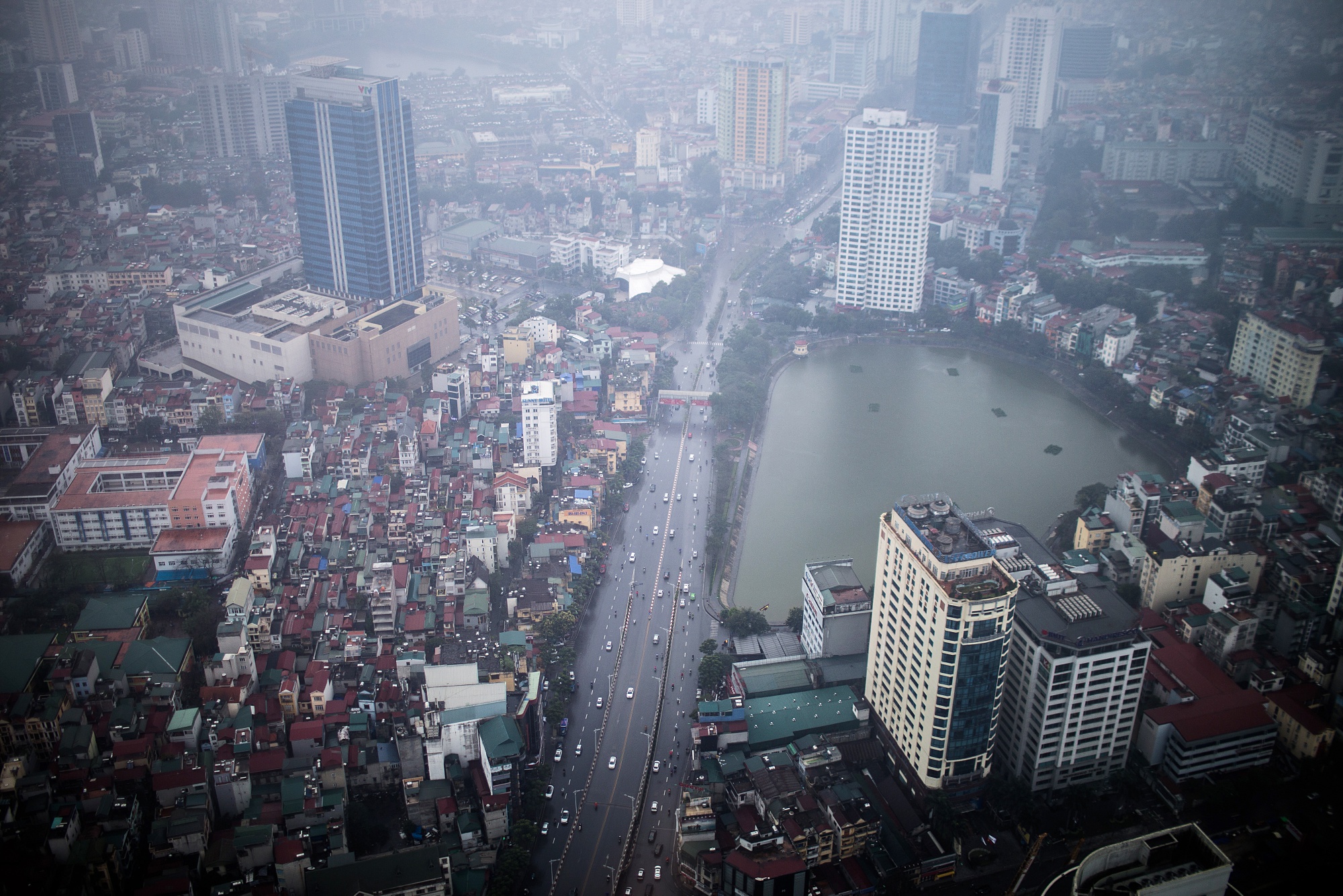 Vehicles travel&nbsp;along a road past buildings seen from the glass-bottomed observation deck of Lotte Center in Hanoi, Vietnam.
