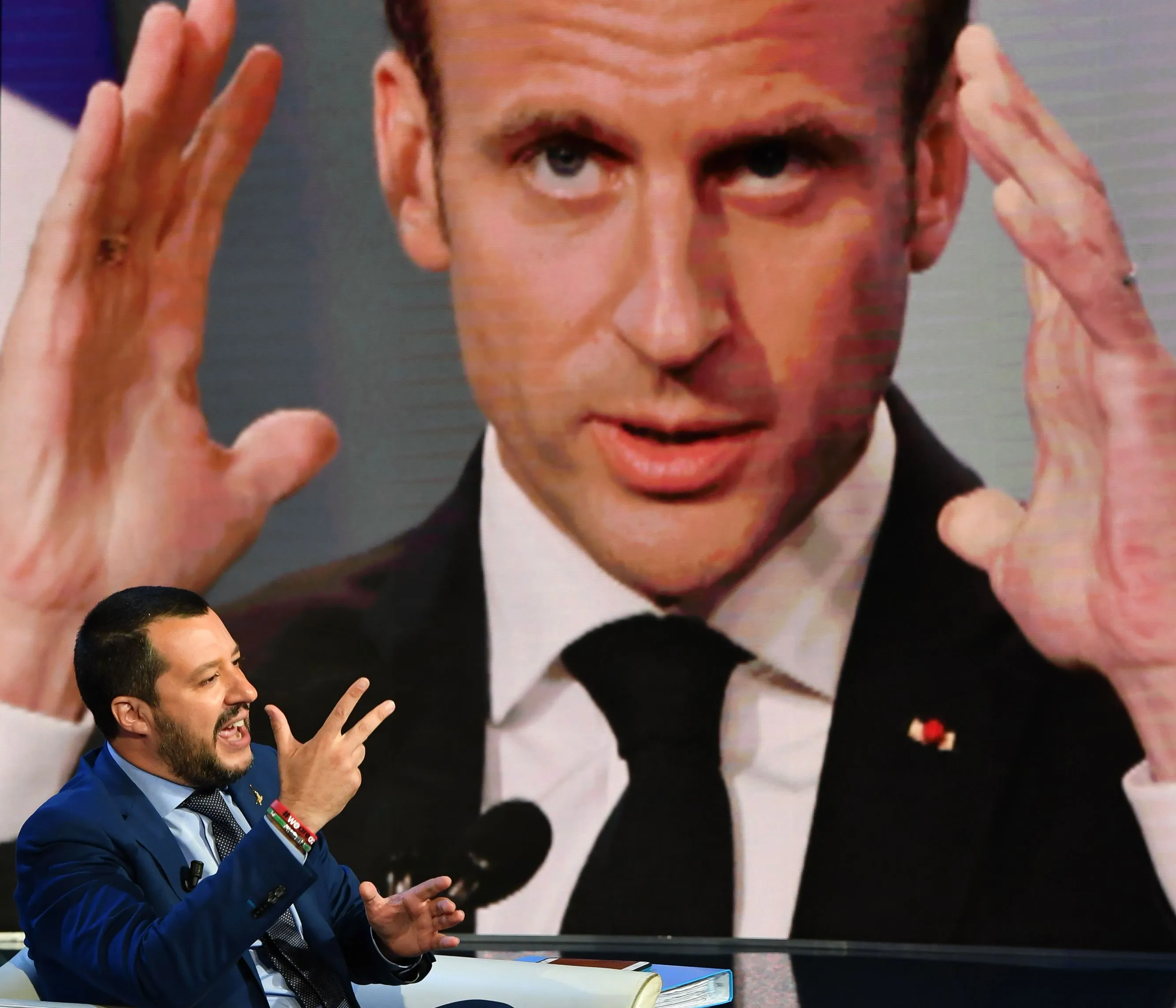 Macron is displayed on a screen as Salvini speaks on a TV set.