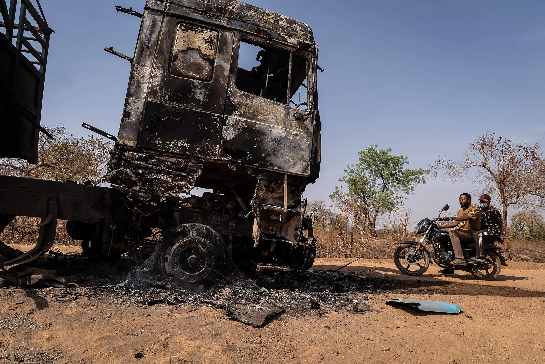 Men ride past a burnt truck following an attack in Woro, Kwara State, Nigeria, on Feb. 5.&nbsp;