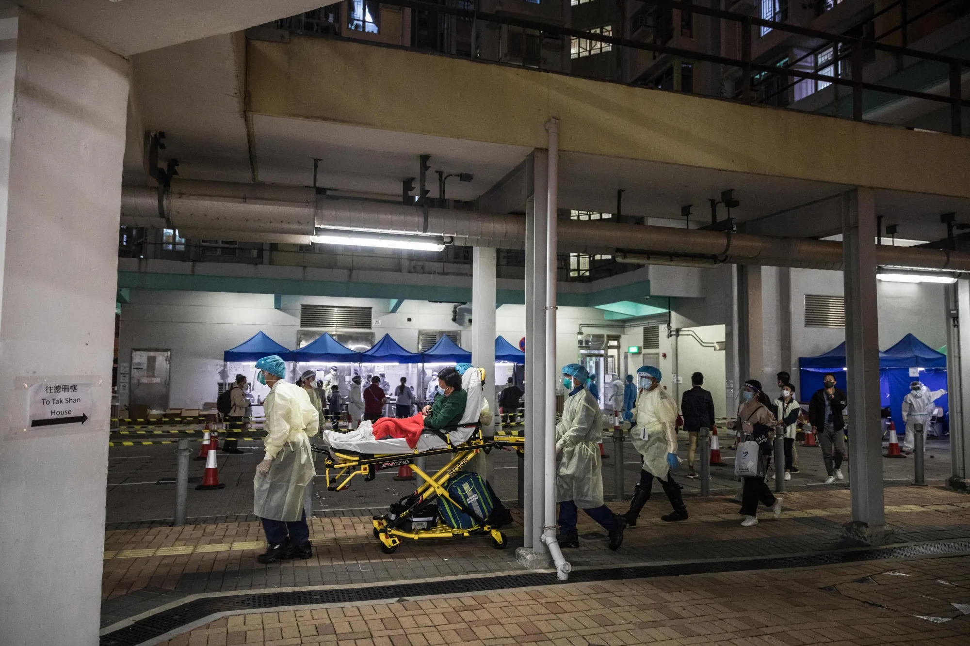 Health workers move a man on a stretcher in a locked down apartment block while residents are tested for Covid-19, in Hong Kong on March 4.