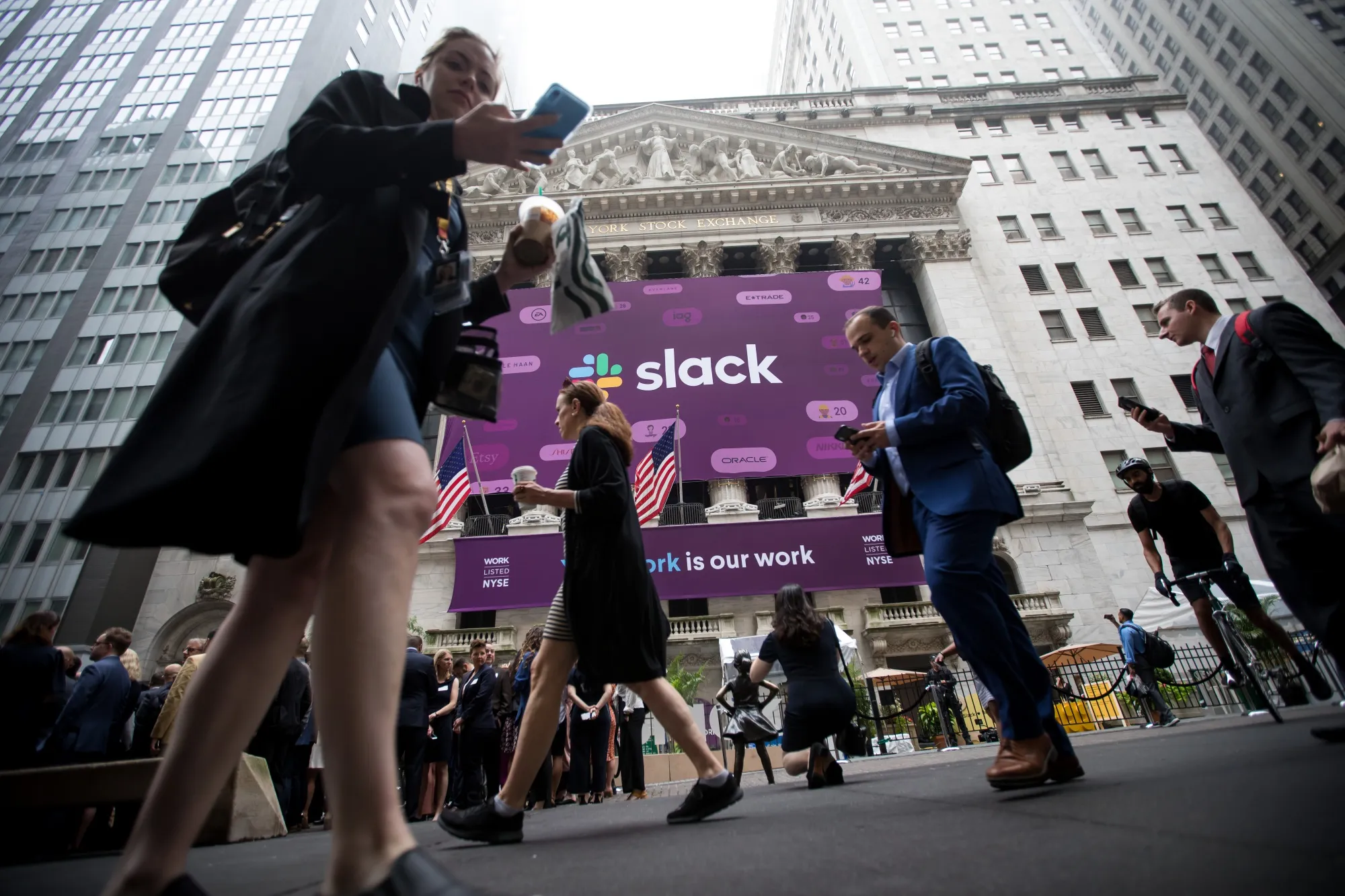 Pedestrians pass in front of a Slack Technologies Inc. signage displayed outside of the New York Stock Exchange during the company's initial public offering in New York on June 20, 2019.