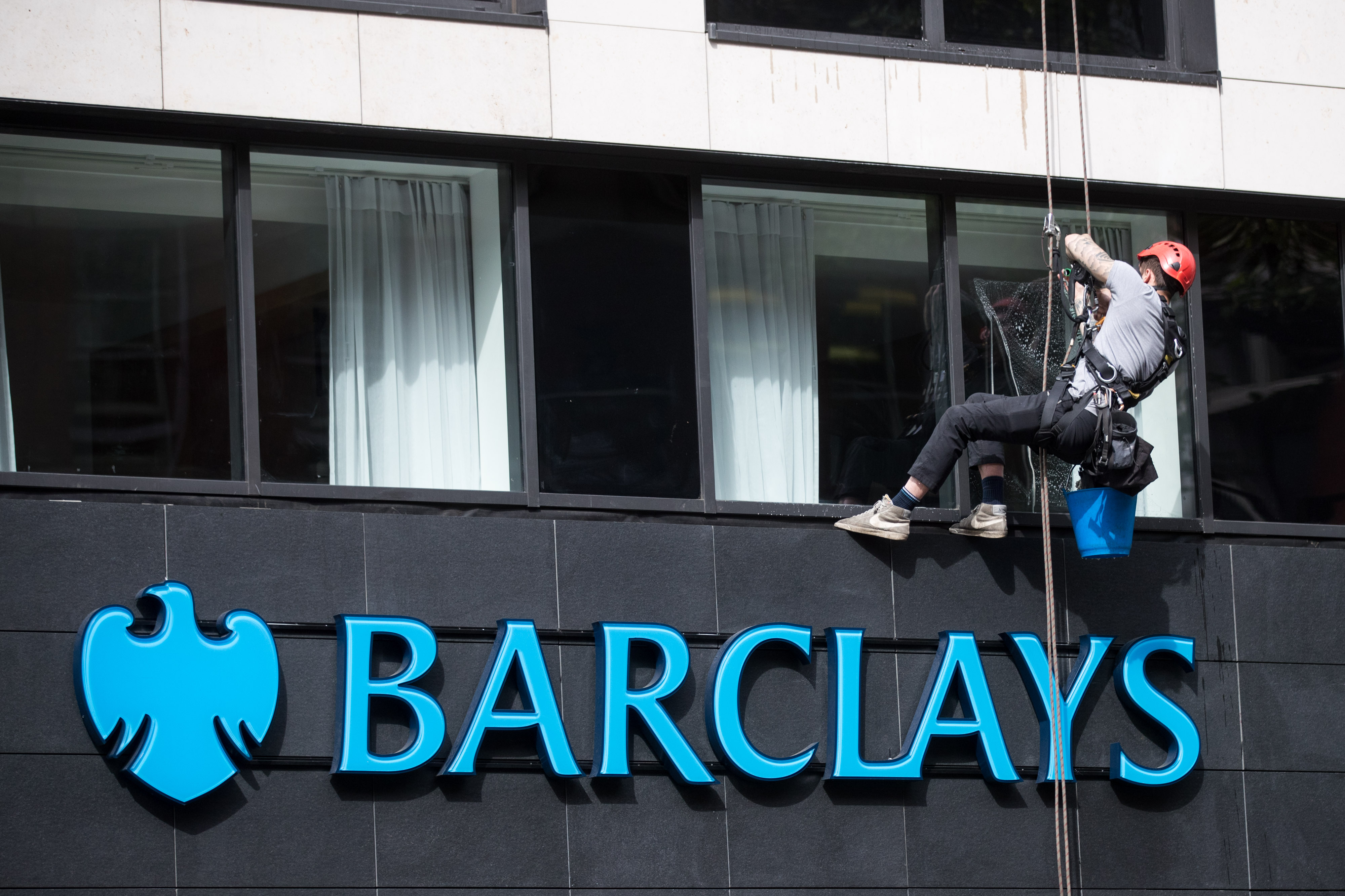 A worker cleans windows at a branch of Barclays Plc in London.