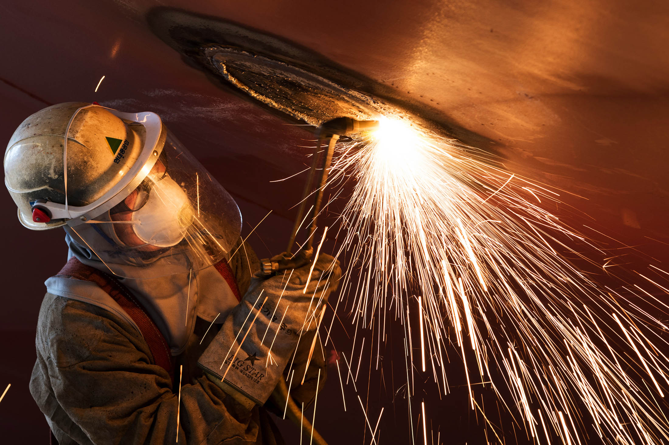 An employee uses a welding torch while working on a ship under construction in the dry dock at the Hyundai shipyard in Ulsan. Industrial production fell 0.3 percent from a year earlier, Statistics Korea said. Output fell 2.1 percent from October, the most since January this year.
