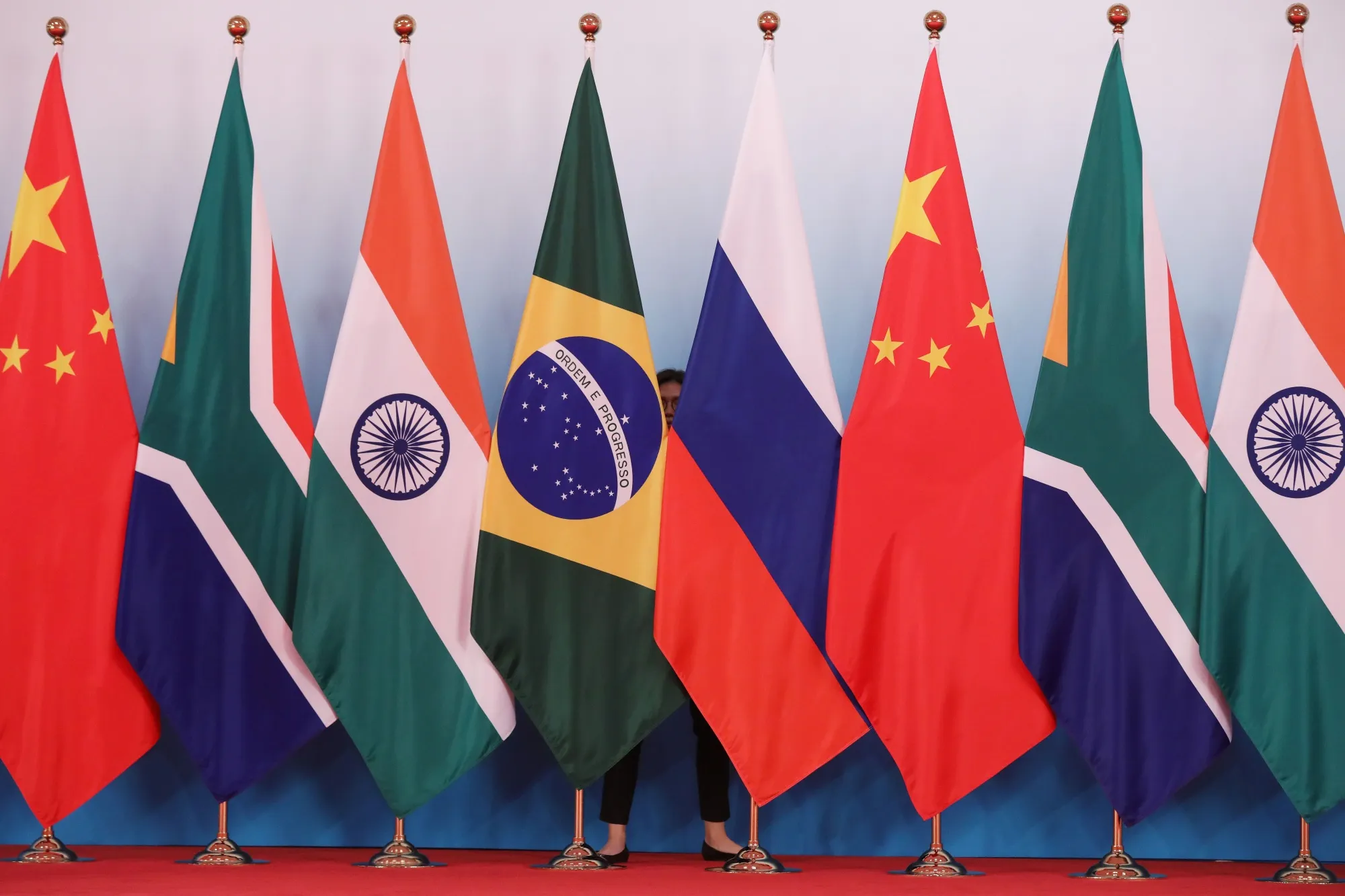 A member of staff stands behind national flags of BRICS countries