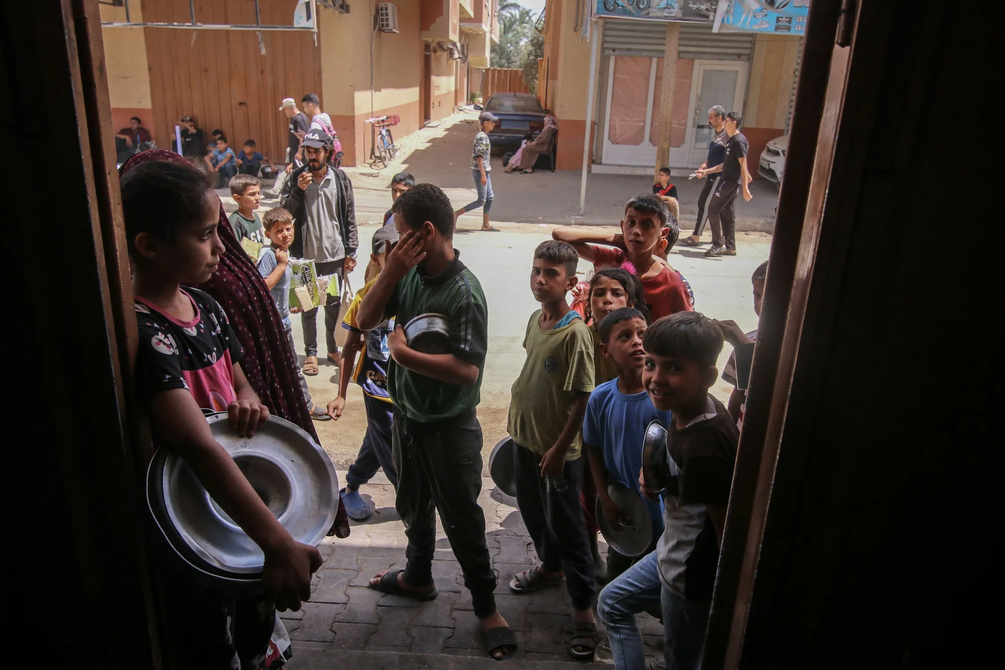 Displaced Palestinians wait to collect free food at a street kitchen.