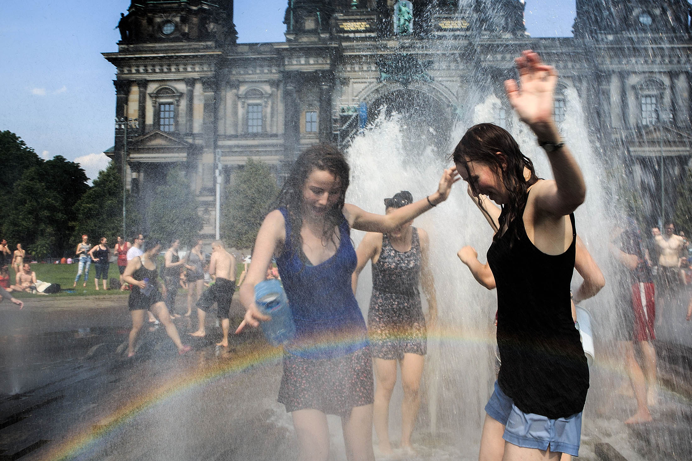People stay cool in the water fountain in Berlin.
