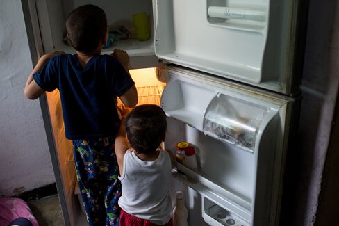 Boys play with the refrigerator at their home in Catia.