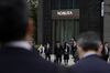 Pedestrians wait for a traffic signal in front of a branch of Nomura Securities Co., a unit of Nomura Holdings Inc., in Tokyo.